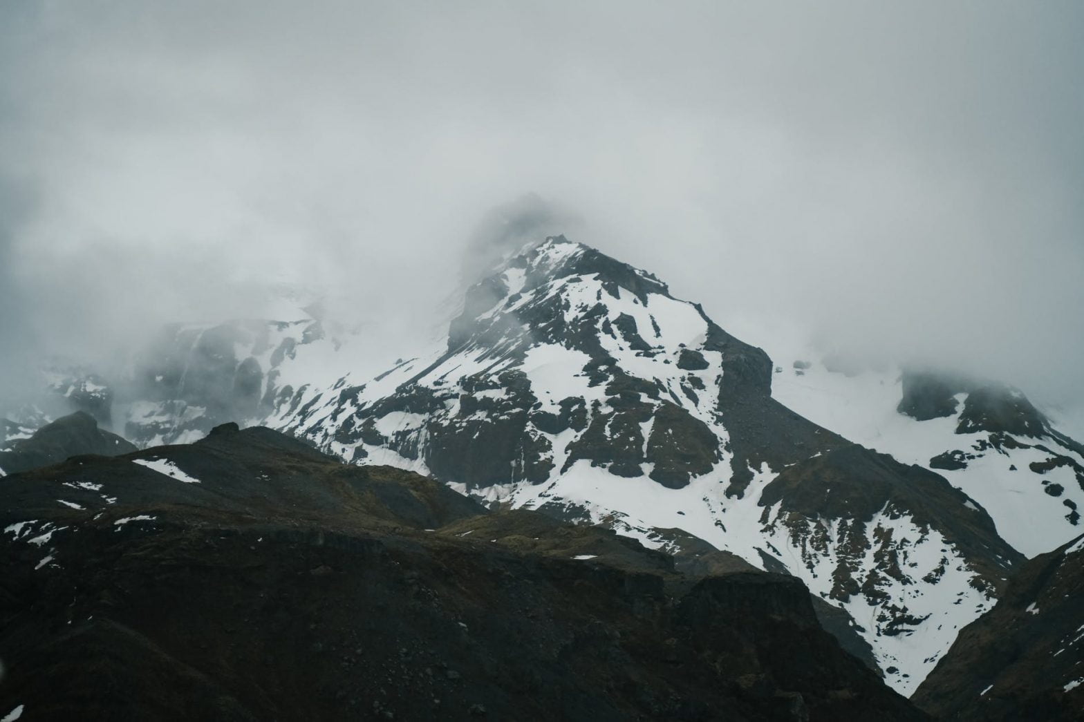 severe snowy mountains under thick clouds